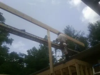 Carpenter setting a ridge beam over a new addition frame — Ice Dam Removal by Roofing Brothers in Atlantic Beach