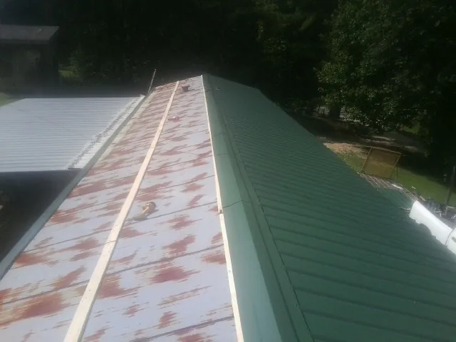 Old rusted panels beside newly installed green metal roofing — Wind Damage Roof Repair by Roofing Brothers in Atlantic Beach